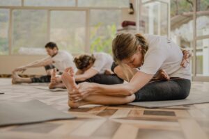 Yoga practitioners performing seated stretching exercises in a peaceful studio, representing certified yoga training, mindfulness, flexibility, and holistic wellness practice.
